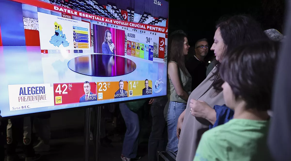 Cateva persoane se uita la un ecran imens pe care este afisat exit poll-ului alegwerilor prezidentiale, București, 4 Mai 2025