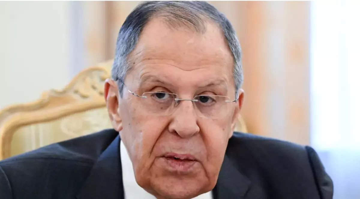 În imagine este ilustrat Serghei Lavrov, îmbrăcat cu costum negru, cămașă albă și poartă ochelari