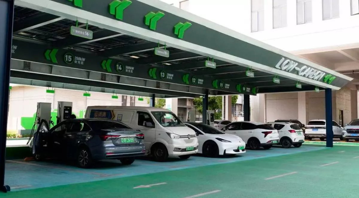 Stație de încărcare pentru mașini electrice din China. În stație sunt conectate mai multe mașini electrice, o dubă albă, un model Tesla S si alte mașini.
