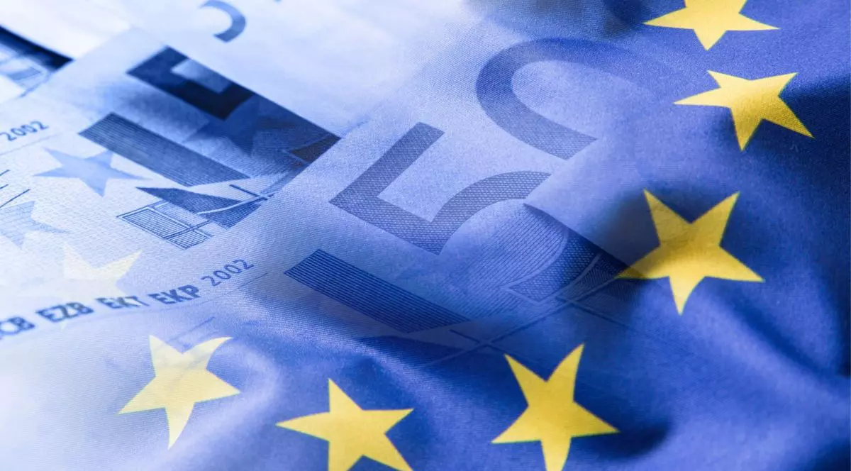 Steagul Uniunii Europene fluturând pe un fundal cu monede euro.