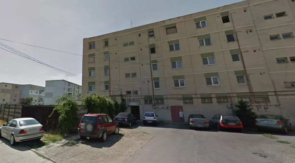 Imagine de pe Google Street View, în care apare un bloc de locuințe, de culoare galbenă, și mai multe mașini parcate pe stradă