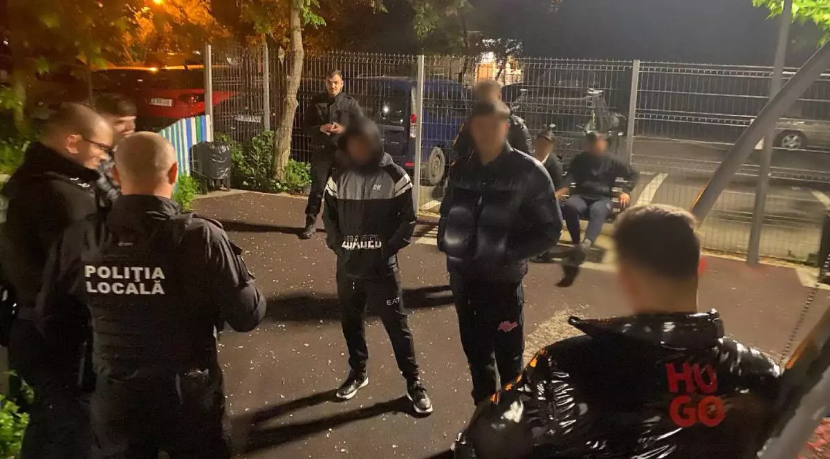 Polițiștii de la Locală Sector 6 în timp ce îi sancționează pe tinerii pe care i-au prins că au făcut covoare de coji de semințe și mucuri de țigară într-un parc din București miercuri seara.