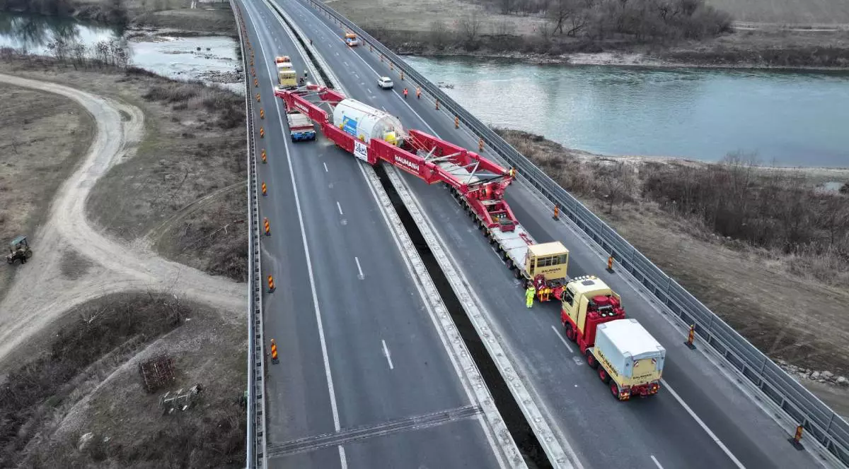Transport agabaritic pe o autostradă, desfășurat pe un pod.Transportul se desfășoară pe diagonală, ocupând ambele sensuri ale autostrăzii