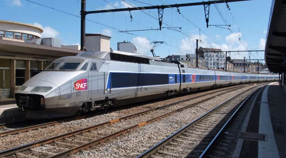 In imagine un tren pe sine de cale ferata si stalpi de electricitate