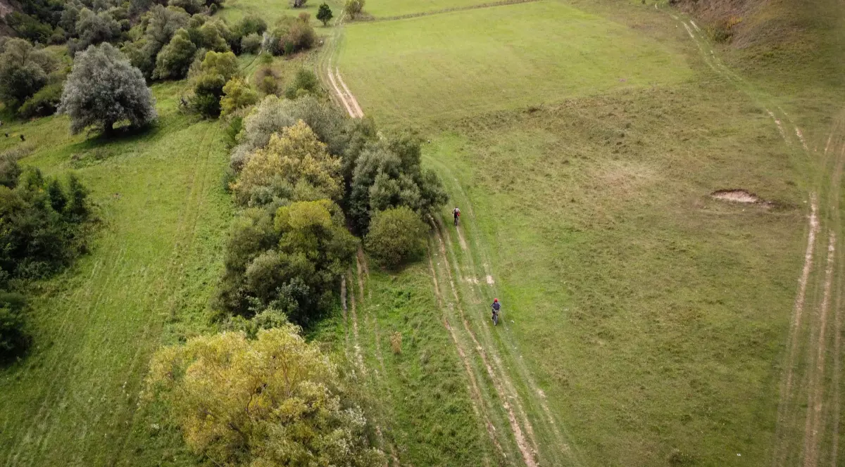 O vedere aeriană care surprinde doi oameni pe bicicletă, pe Via Transilvanica.