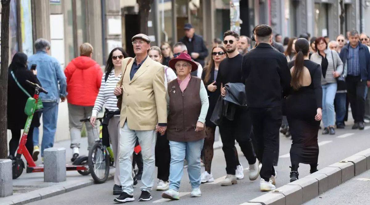 Mai mulți oameni se plimbă pe stradă, unii îmbrăcați cu geci, iar în prim-plan se vede un cuplu de pensionari și în spatele lor, mulți tineri, pe Calea Victoriei, București, 13 aprilie 2025.
