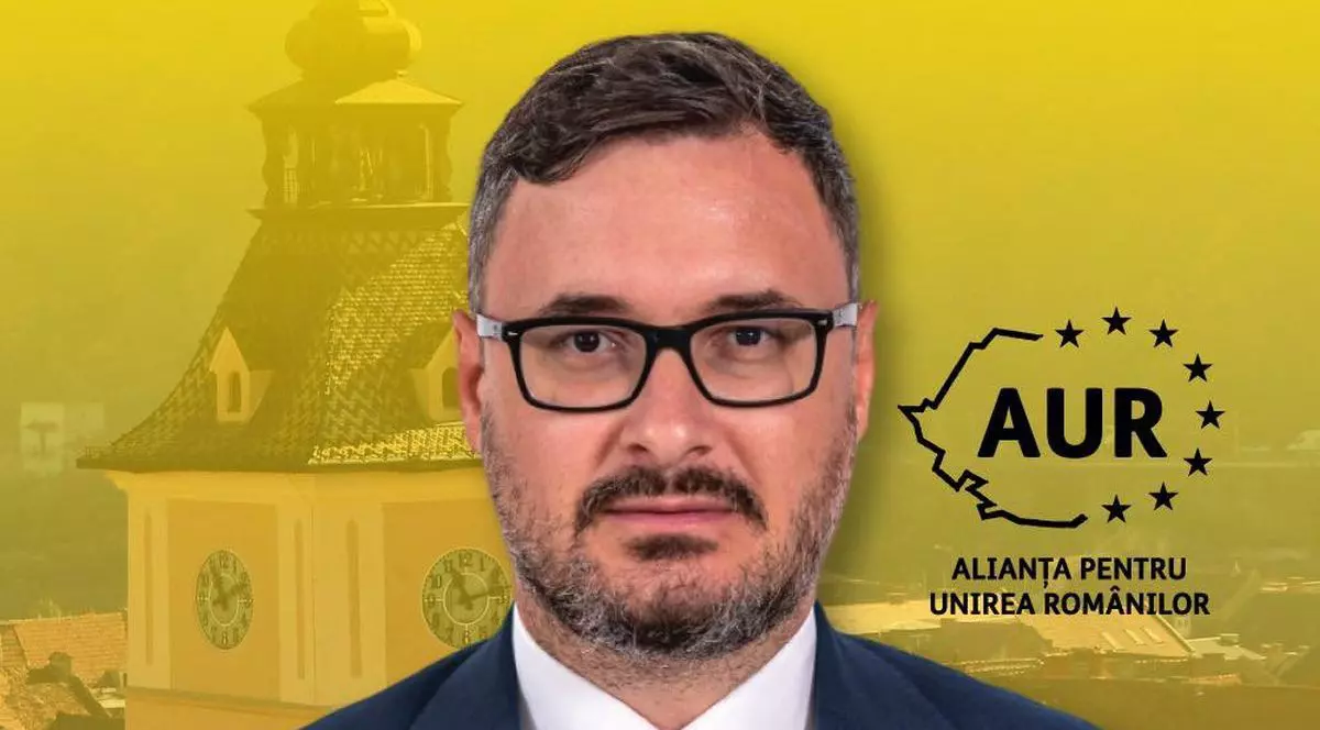 Dan Tanasă, purtător de cuvânt al AUR, îmbrăcat la costum, având în fundal o imagine din centrul orașului Brașov
