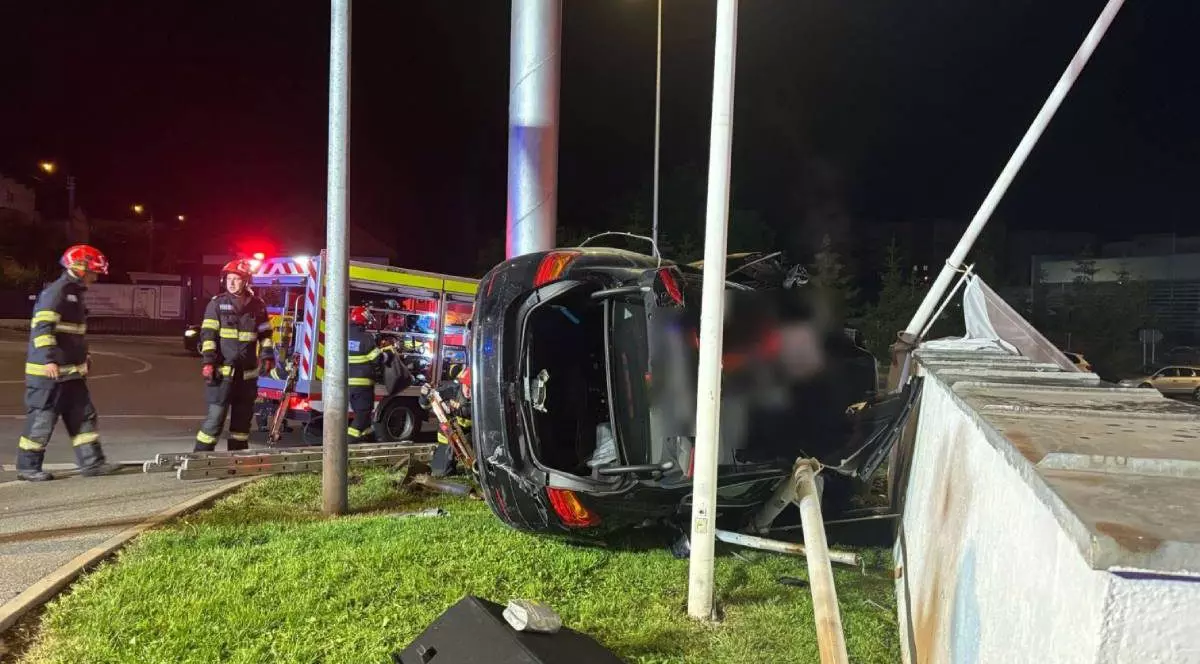 Imagine cu mașina răsturnată și cu doi salvatori la fața locului