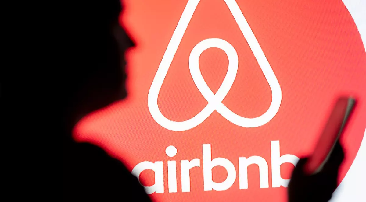 o femeie se uită la un smartphone cu logo-ul Airbnb afișat în fundal