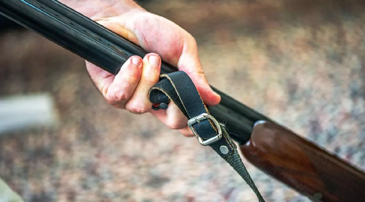 Un bărbat curăță meticulos o pușcă veche folosind ulei și gadgeturi de curățare, prezentând atenția la detalii și măiestria armelor de foc de epocă.