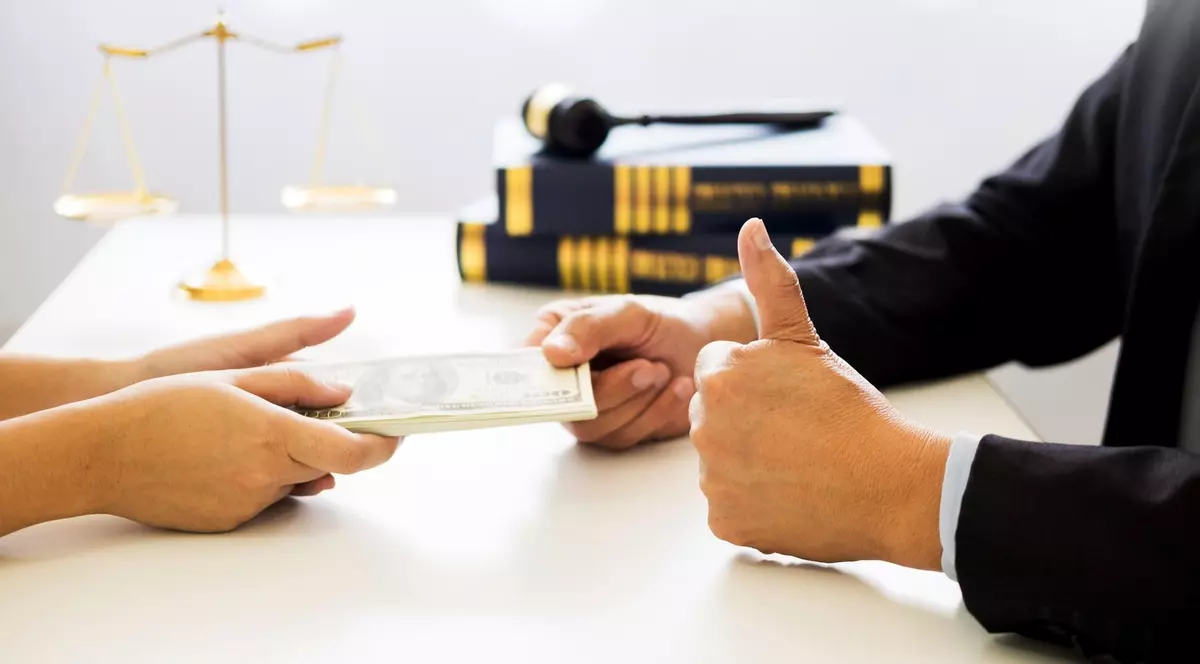 Poză cu un avocat (dreapta) care primește bani de la un client (stânga)