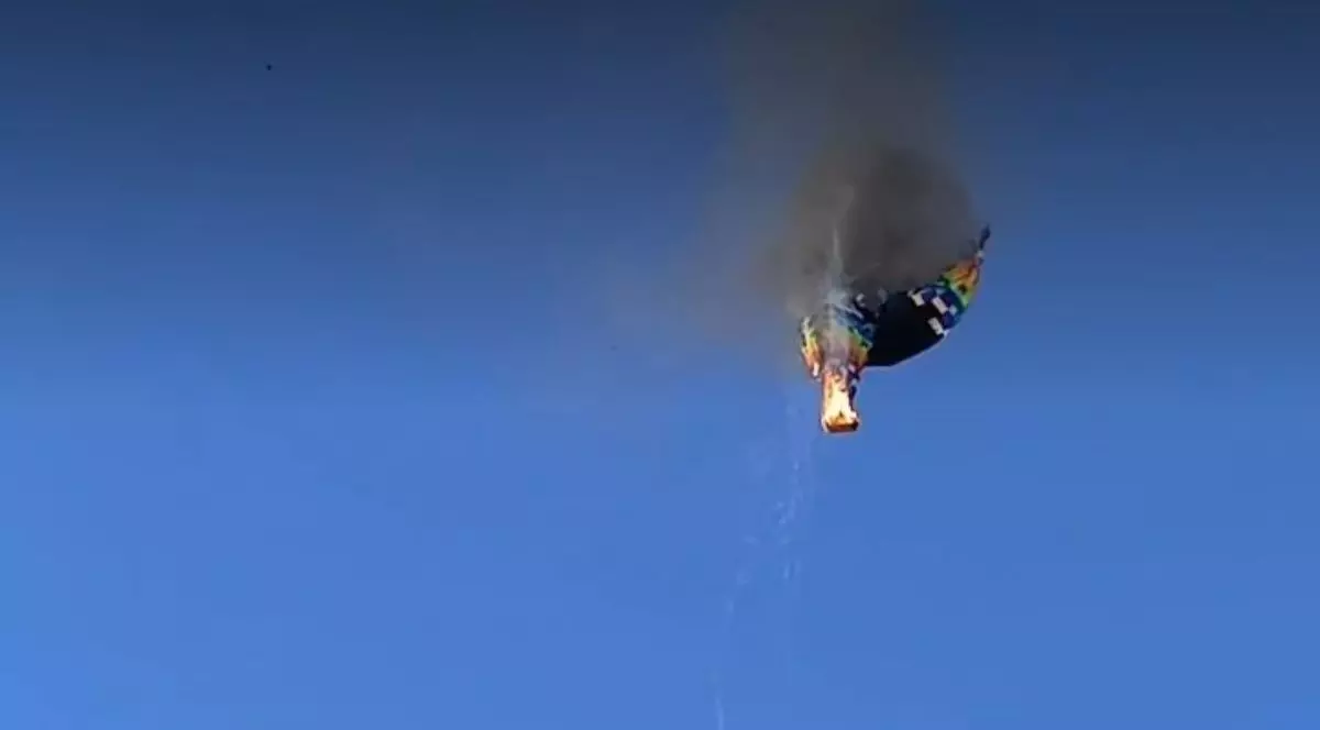 Un balon cu aer cald, cu coșul în flăcări, din care iese fum negru