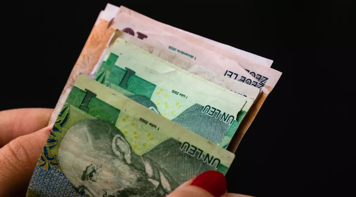 O femeie numără bani, bancnote românești, pe un fundal negru