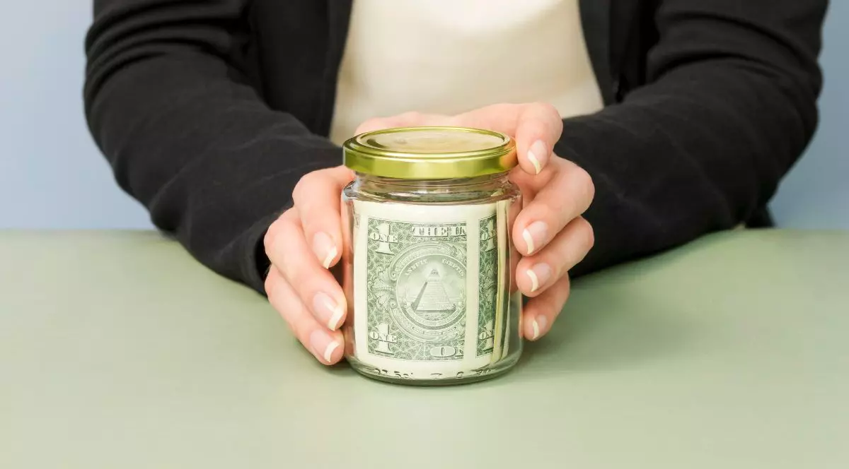 Borcan cu bacșiș ținut în mâini de o femeie, pe o tejghea