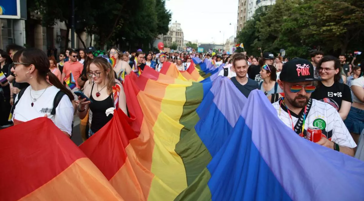 oameni care poartă un steag cu culorile curcubeului în timpul paradei Bucharest Pride 2025