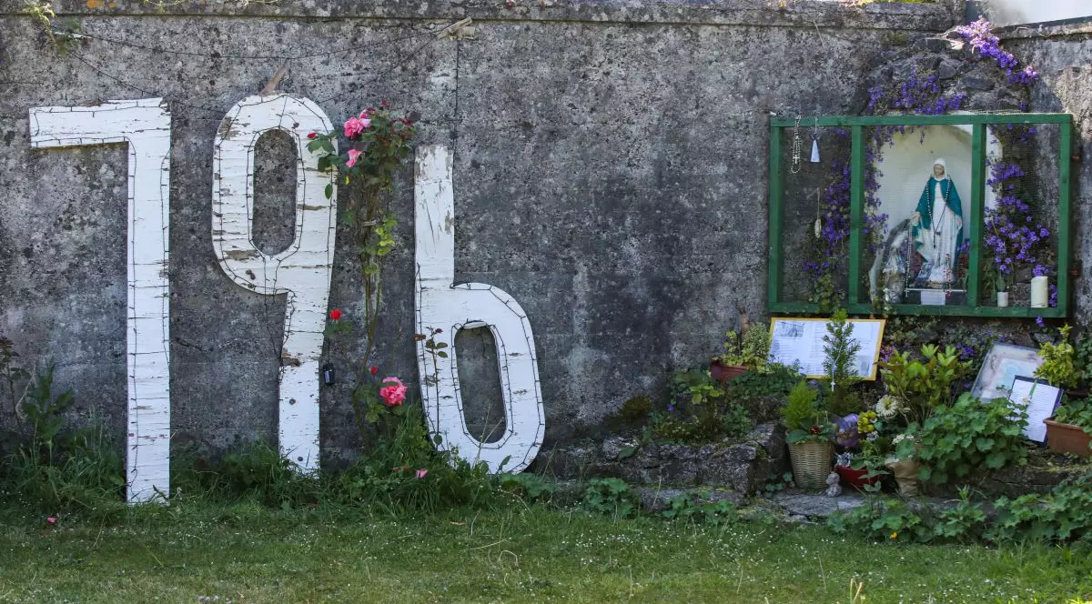 Numărul 796 reliefat prin culoare albă, pe gardul de piatră al căminului pentru mame singure din Irlanda, în luna iunie 2025