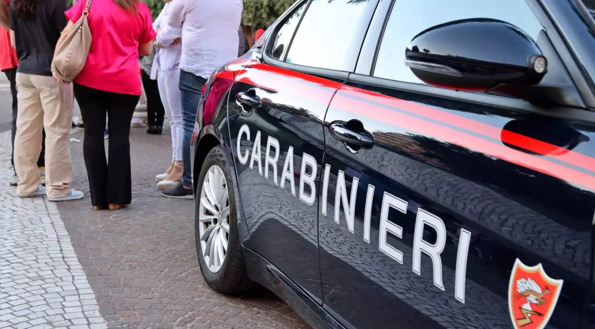 Carabinierii au oprit o femei și un bărbat lângă mașină și discută cu ei, acestia stau cu spatele.