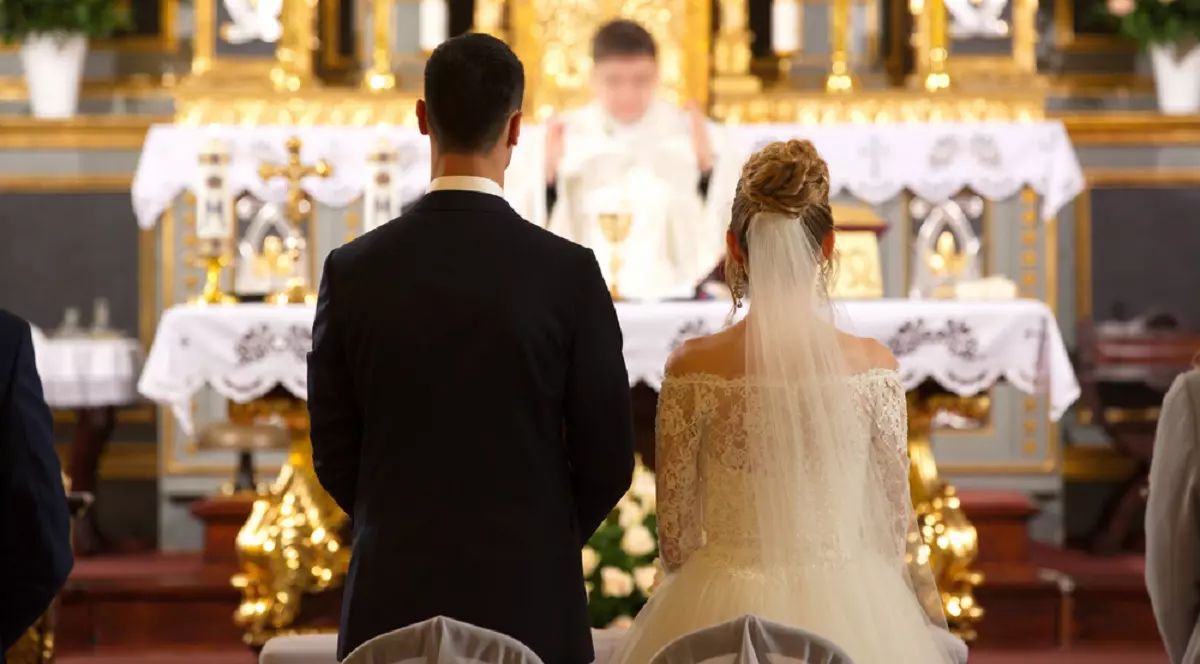 De ce este greşit să le urezi mirilor „casă de piatră” - Imagine cu doi miri aflaţi în faţa altarului, la cununia religioasă