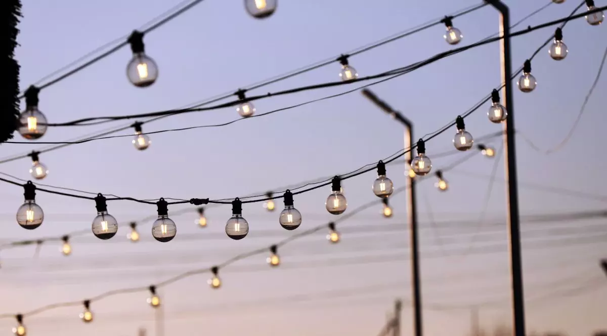 Mai multe fire electrice pe care se văd becuri aprinse, la răsărit