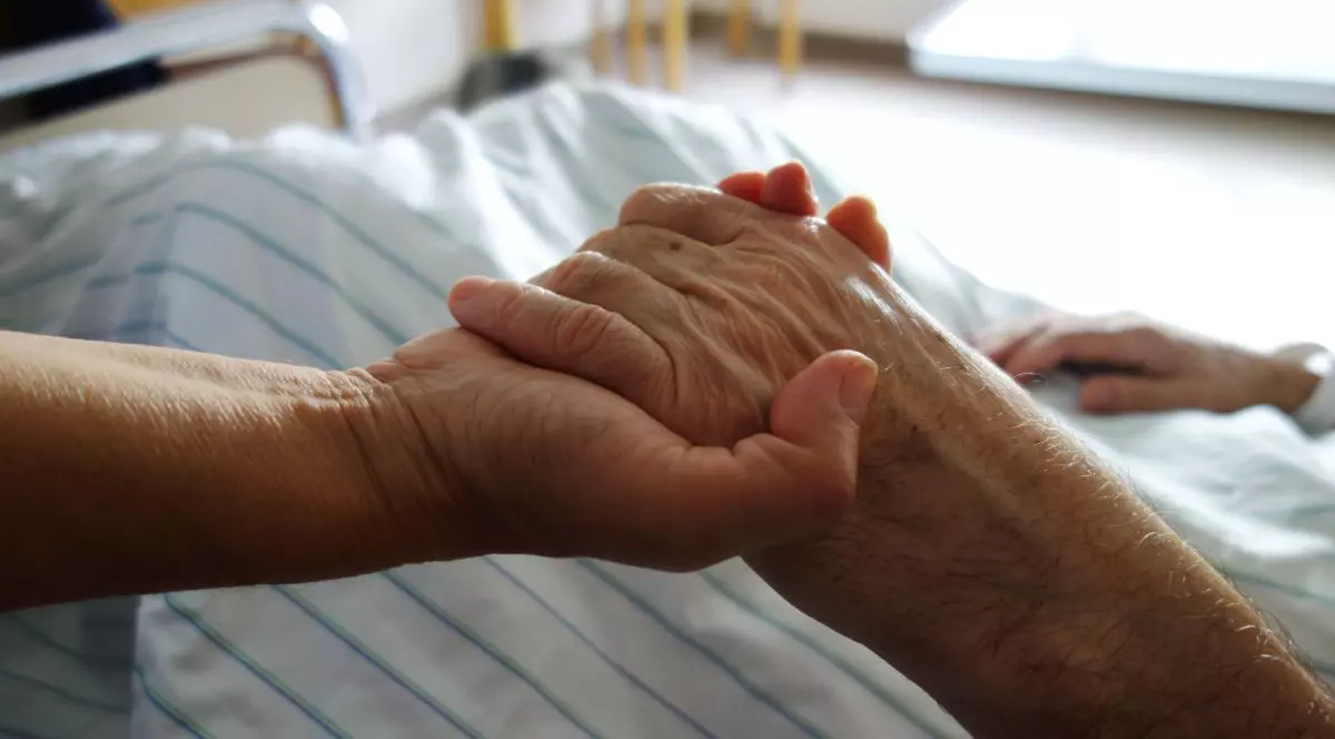 Conceptul de sinucidere asistată. o asistentă ține mâna unei persoane in varsta