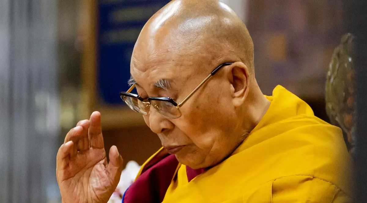 Dalai Lama, îmbrăcat în robă galbenă, în timpul unei rugăciuni