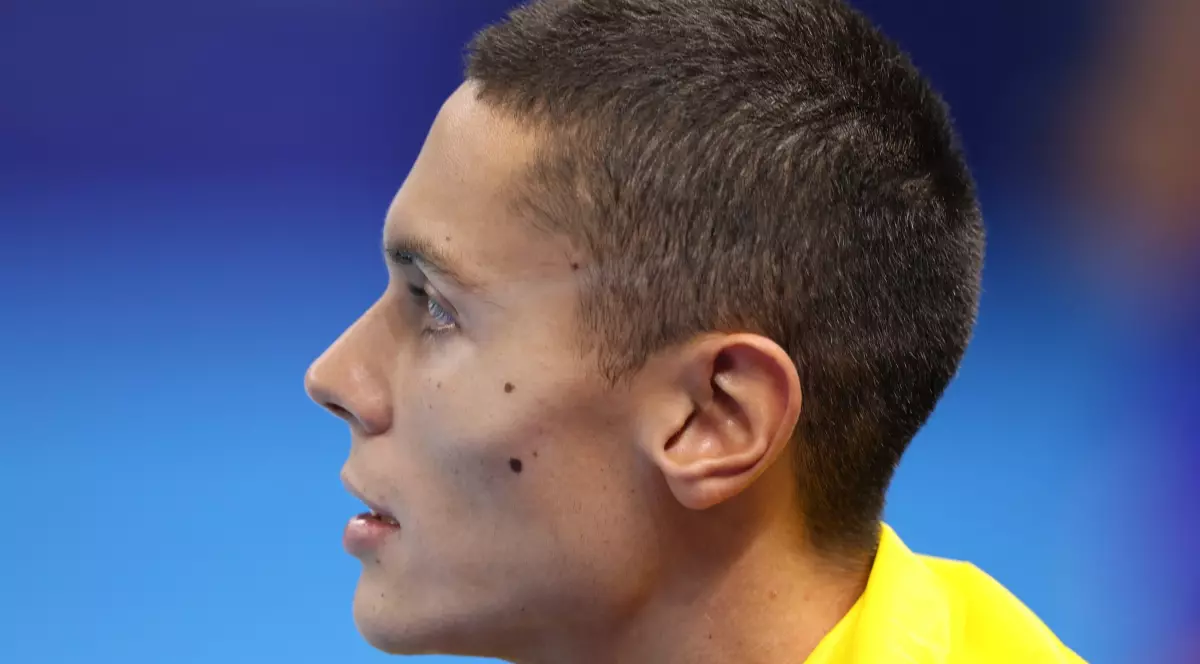 David Popovici, văzut din profil, cu steagul României pe umeri