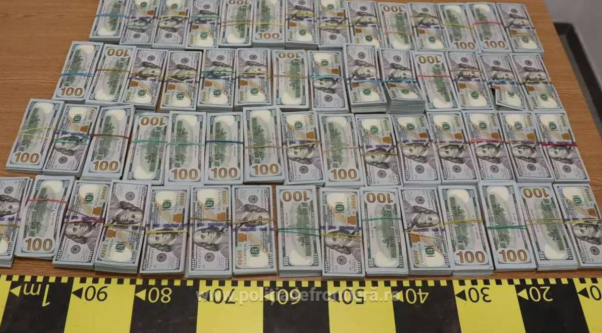 Imagine cu banii găsiți de polițiștii de frontieră în cartușele de țigări. Bancnotele sunt întinse pe o masă