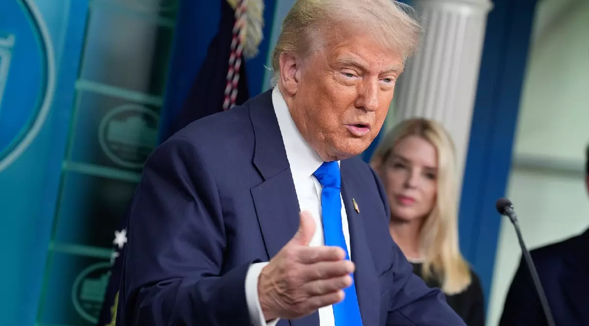 Donald Trump îmbrăcat într-un costum albastru cu o cămașă albă și o cravată albastra într-o conferință