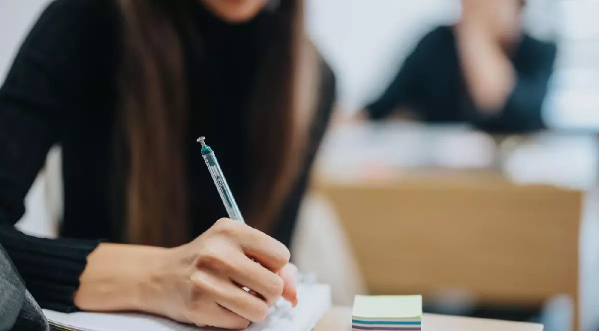 O elevă ia notițe în timpul orei, în sala de clasă