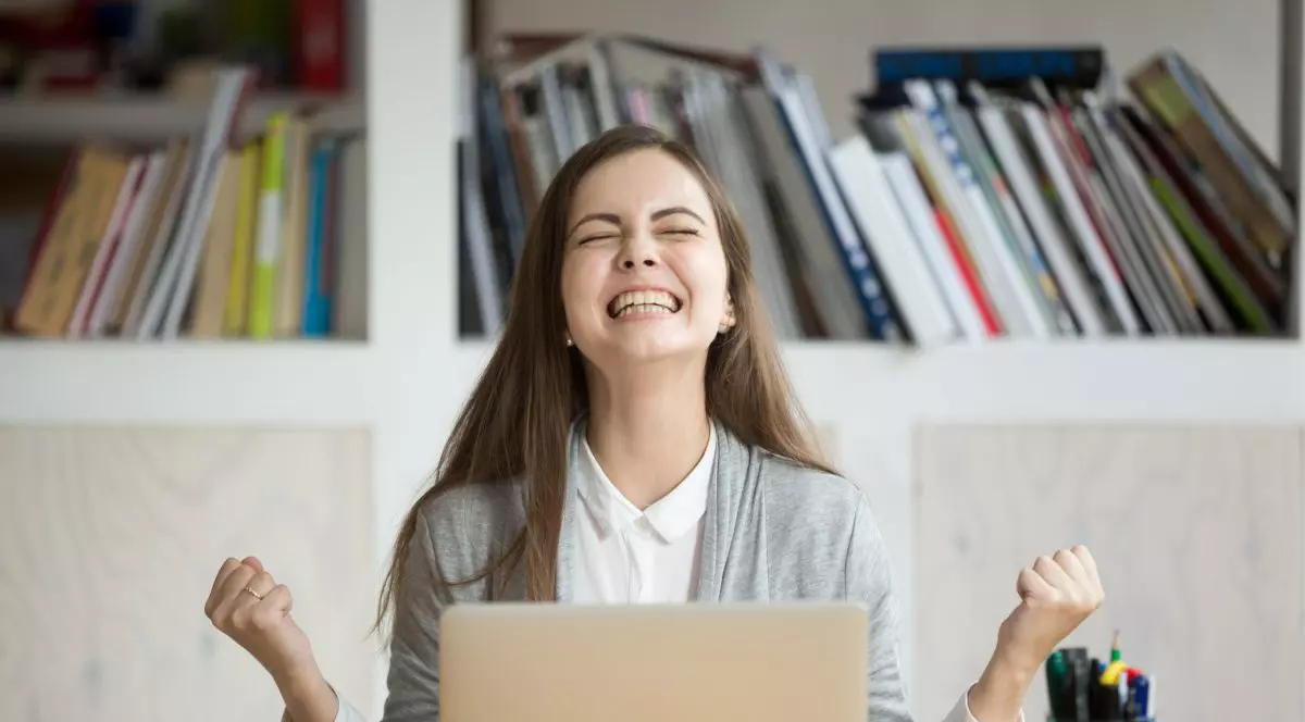 Eleva care se afla in fata unui laptop si rade fericita