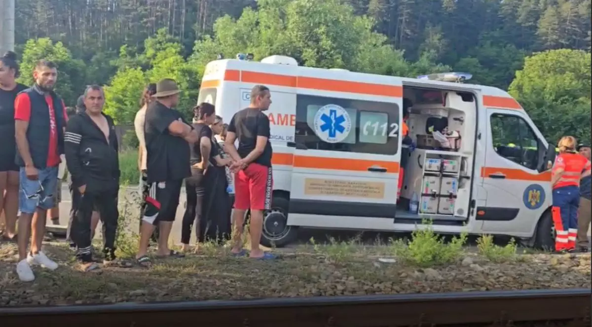 O ambulanță cu ușa deschisă și medic lângă ea este la accidentul de cale ferată din Comănești și mai mulți oameni s-au strând acolo, la locul tragediei, 15 iunie 2025