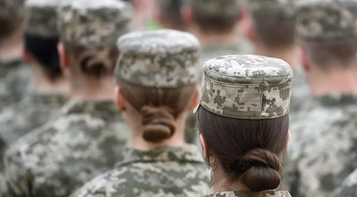 Imagine cu patru femei care stau una în spatele celeilalte. Acestea poartă uniforme militare și au părul strâns în coc