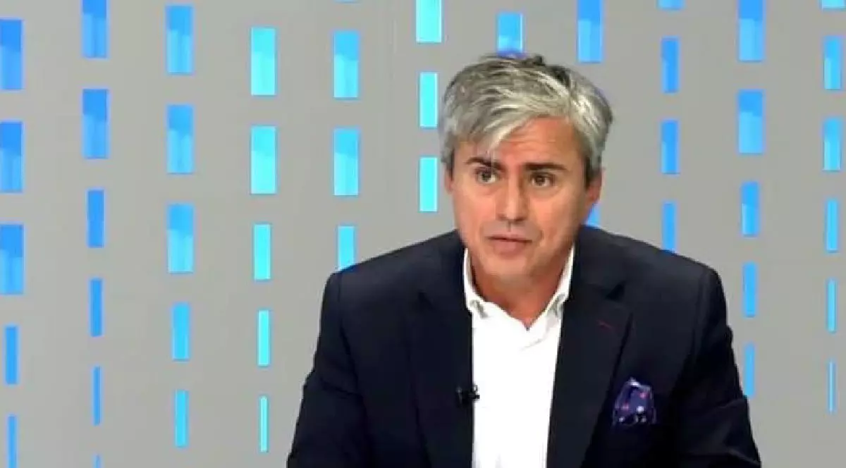 Gabriel Biriș îmbrăcat în sacou negru, cămașă albă, într-un studio TV