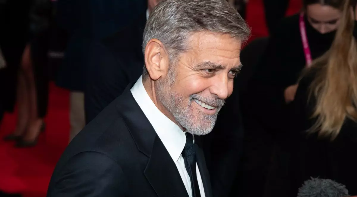 George Clooney zânbește îmbracat în sacpu negru, cravata neagră si camasă alba