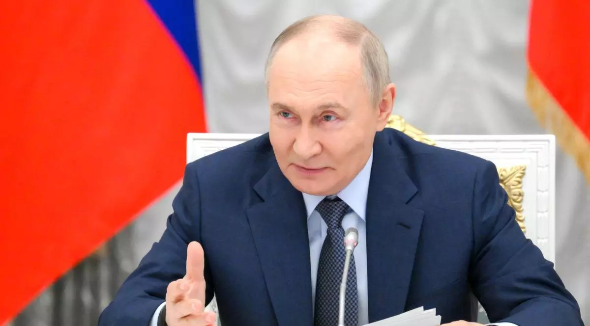 Președintele rus Vladimir Putin, îmbrăcat la costum și ținând în mână mai multe foi, vorbește în timpul unei conferințe la Kremlin, stând pe un scaun și având în spate steagul Federației Ruse Vladimir Putin - iunie 2025