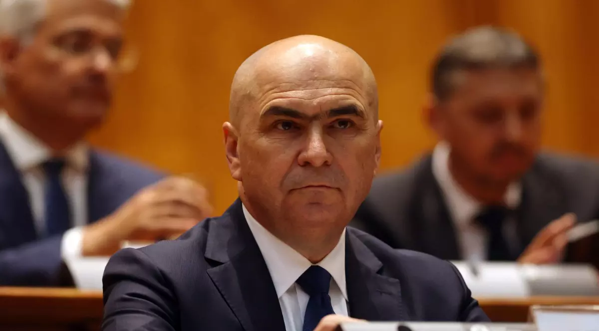 Premierul Ilie Bolojan, în costum negru, cămașă albă și cravată