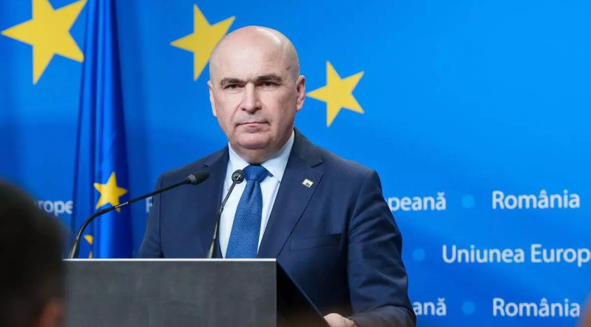 Ilie Bolojan în timpul unei conferințe de presă în Parlamentul European, poartă un costum și o cravată albastră.