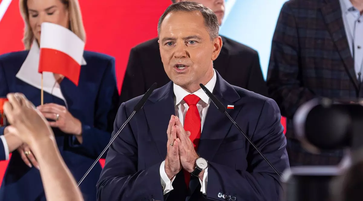 Karol Nawrocki, îmbrăcat într-un sacou negru, o cămașă albă și o cravată roșie, cu mâinile împreunate, ținând un discurs, iunie 2025