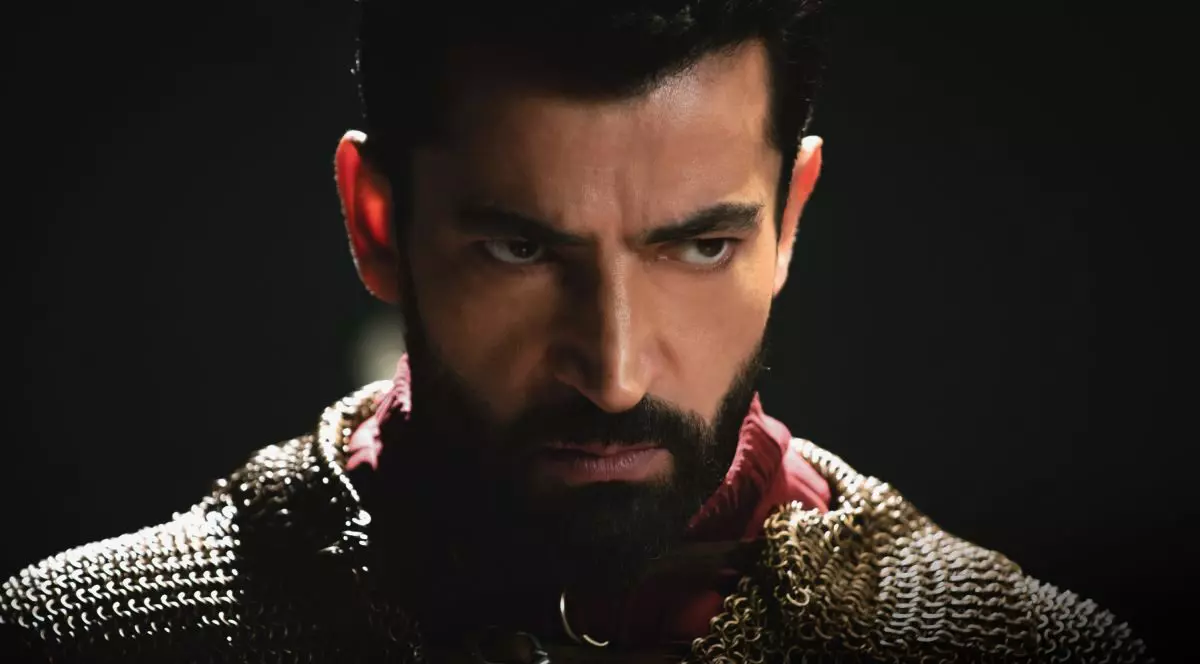 Prim plan cu actorul Kenan İmirzalıoğlu, pe fundal negru, semi-intunecat
