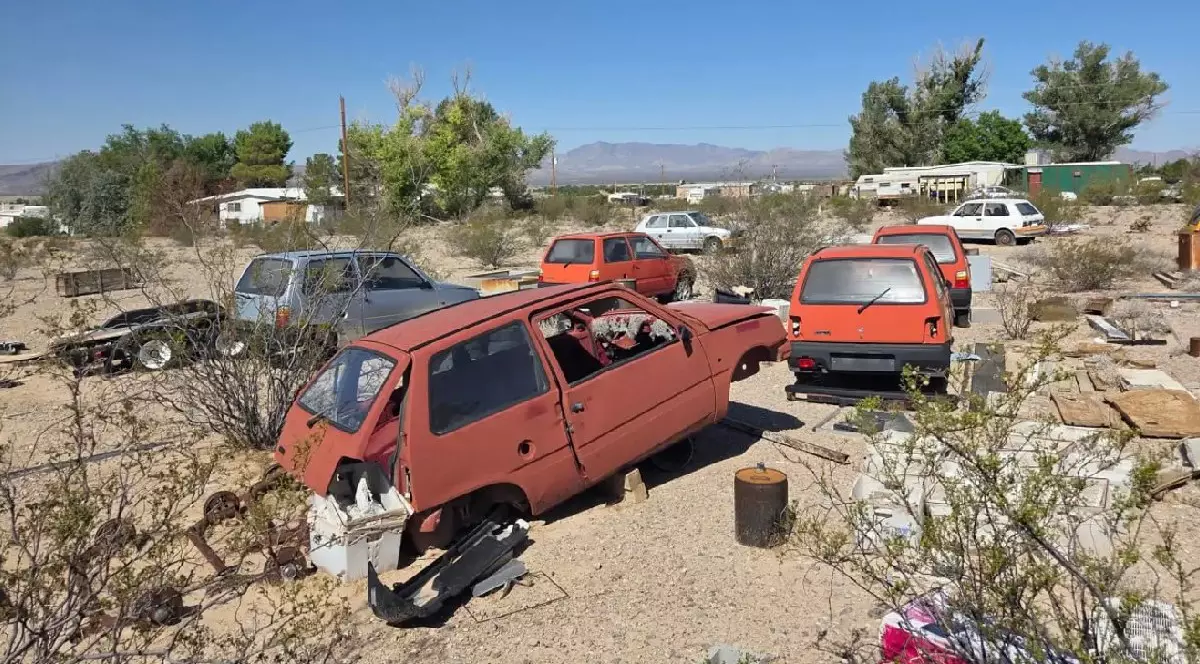 Mașini ruginite stau în soare, într-un cimitir de mașini