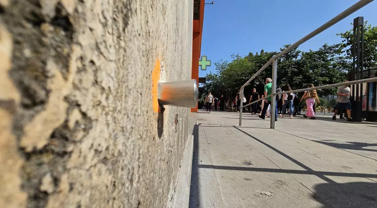 În partea stângă este un senzor montat pe peretele unei clădiri vechi, care monitorizează lucrările care au început la planșeul Unirii, în partea dreaptă sunt oameni care merg pe stradă într-o zi caldă de vară, se vede o bară metalică și semnul unei farmacii