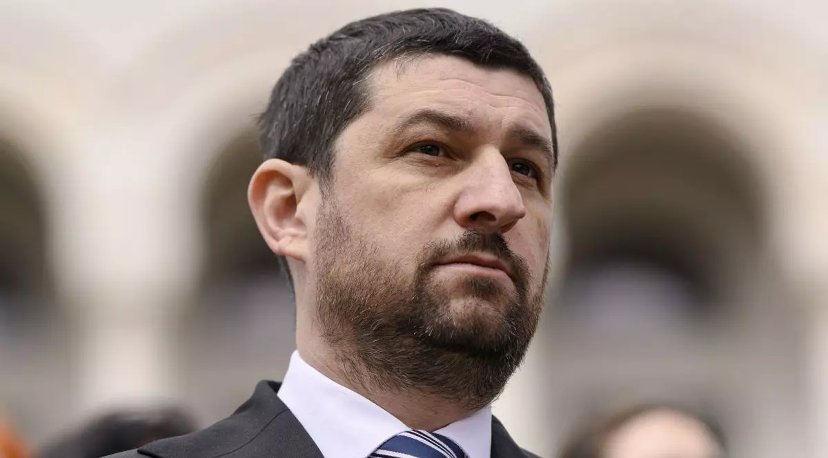 Marius Lulea, vicepreședintele AUR, în prim plan, îmbrăcat cu costum, cămașă albă și cravată albastră