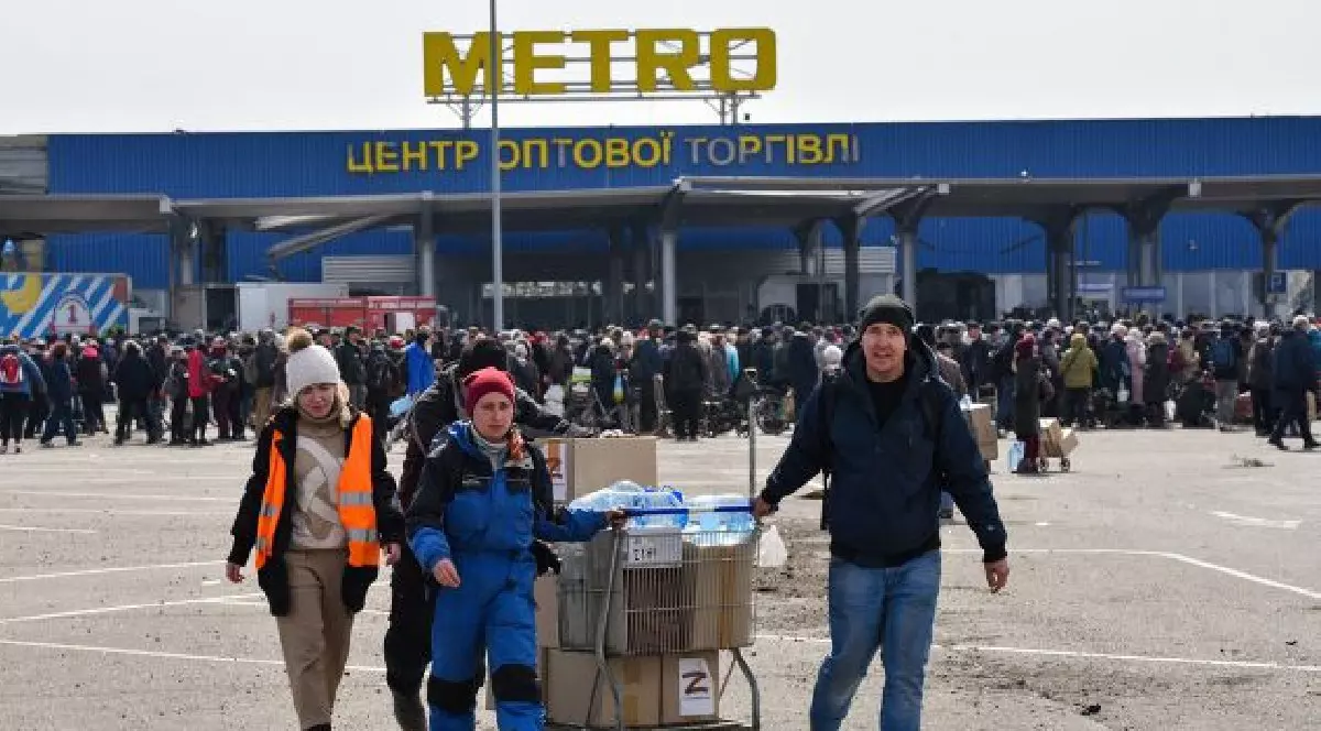 Patru oameni împing un cărucior plin în parcarea unui magazin Metro din Ucraina