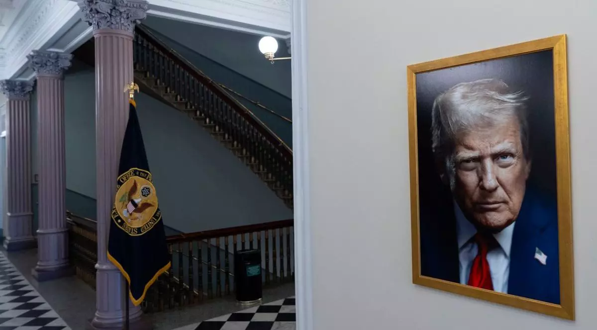 Interior de la CAsa alba, in stanga se vad niste scari si un steag, in dreapta noul portret al lui Donald Trump pe un perete
