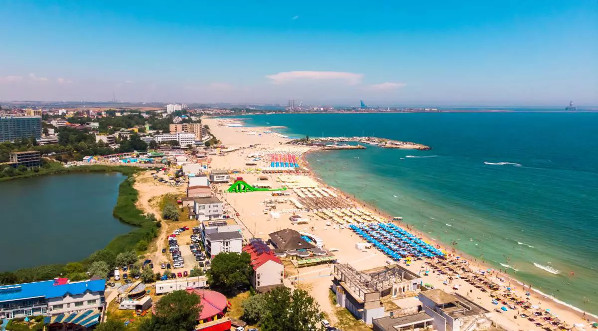 Faleza și plaja din Eforie Nord în timpul sezonului estival, șezlongurile și umbrelele sunt așezate pe plajă.