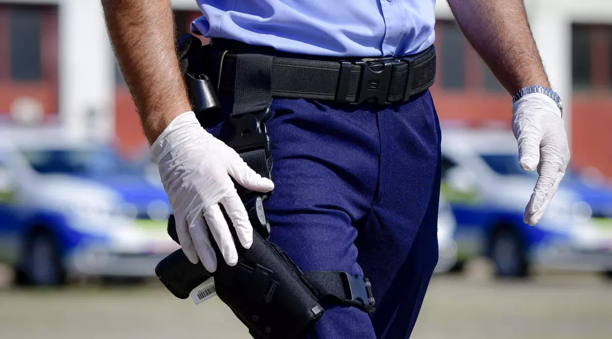 Polițist pozat de la abdomen în jos. Agentul poartă mânuși albe și ține mâna pe tocul pistolului