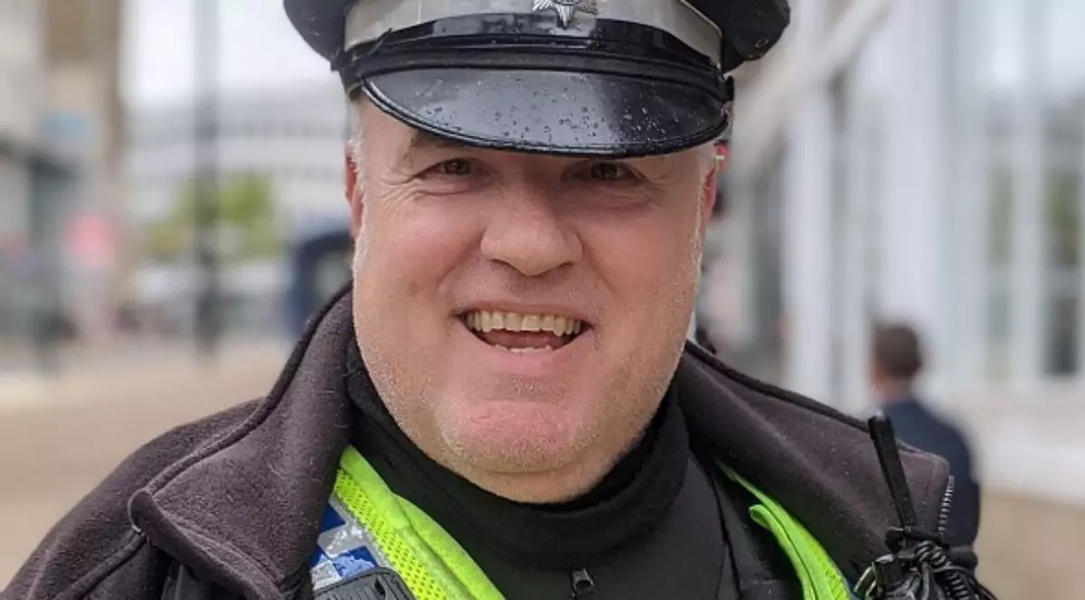 Un bărbat imbrăcat in uniforma britanica de politist, zambeste larg