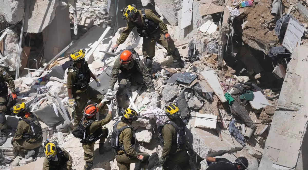 Pompierii intervin în fața unei clădiri dărâmate din Israel și încearcă să vadă dacă găsesc supraviețuitori în grămadă de moloz