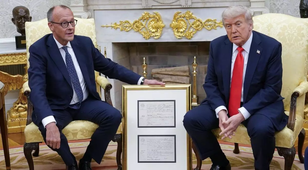 Cancelarul german Friedrich Merz îi înmânează președintelui Statelor Unite, Donald Trump, certificatul de naștere al bunicului președintelui, „Născut în 1869”, în Biroul Oval al Casei Albe din Washington.