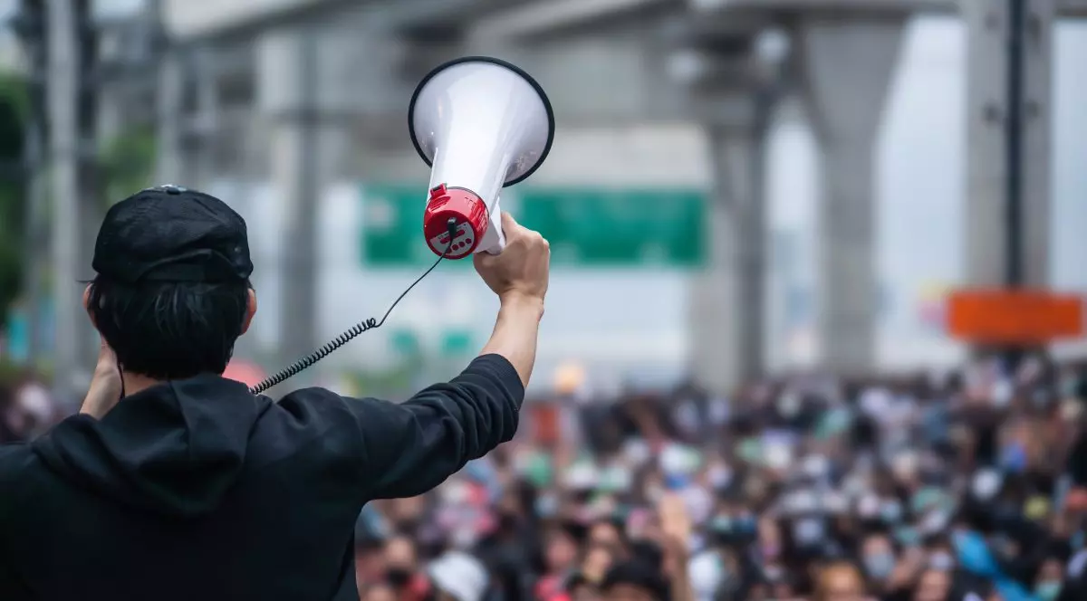 Bărbat care stă cu spatele și vorbește la megafon în timpul unui protest